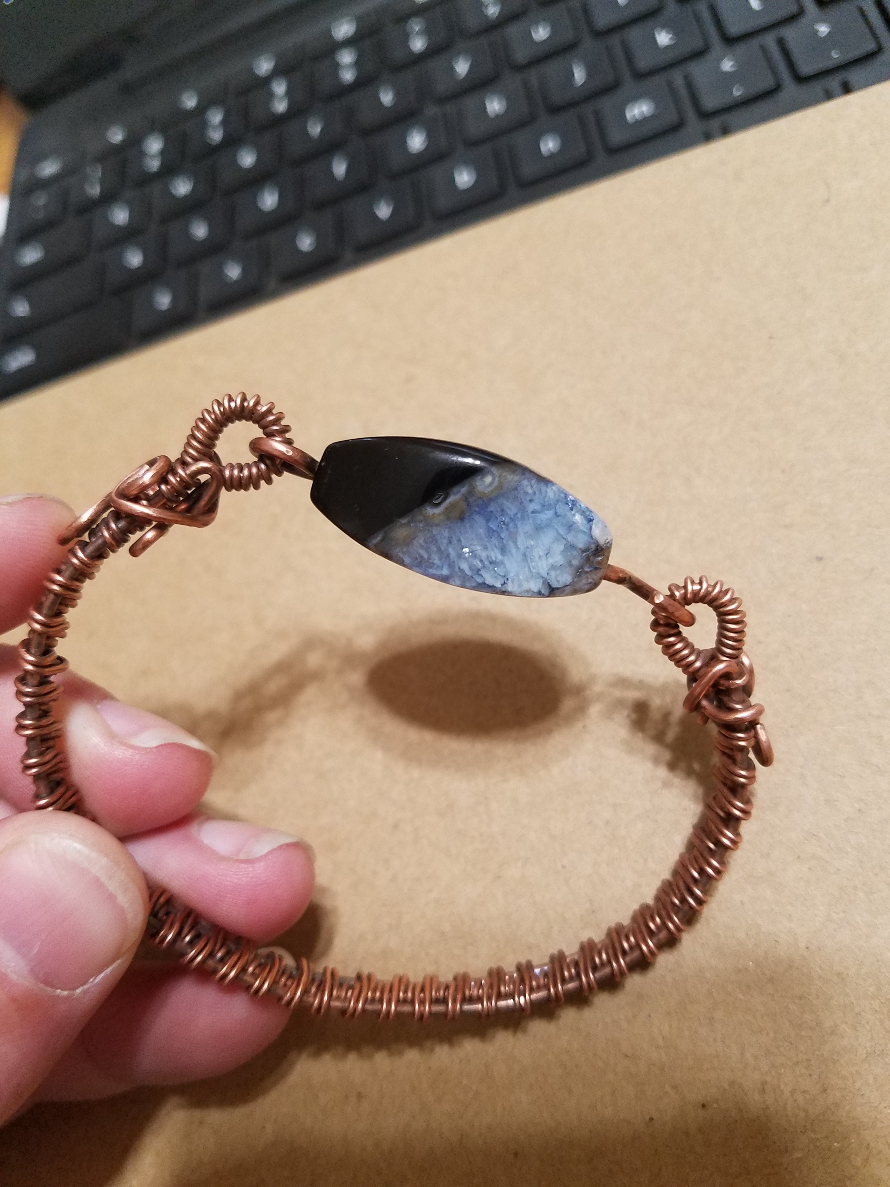 Slender woven copper bracelet with gemstone bead clasp