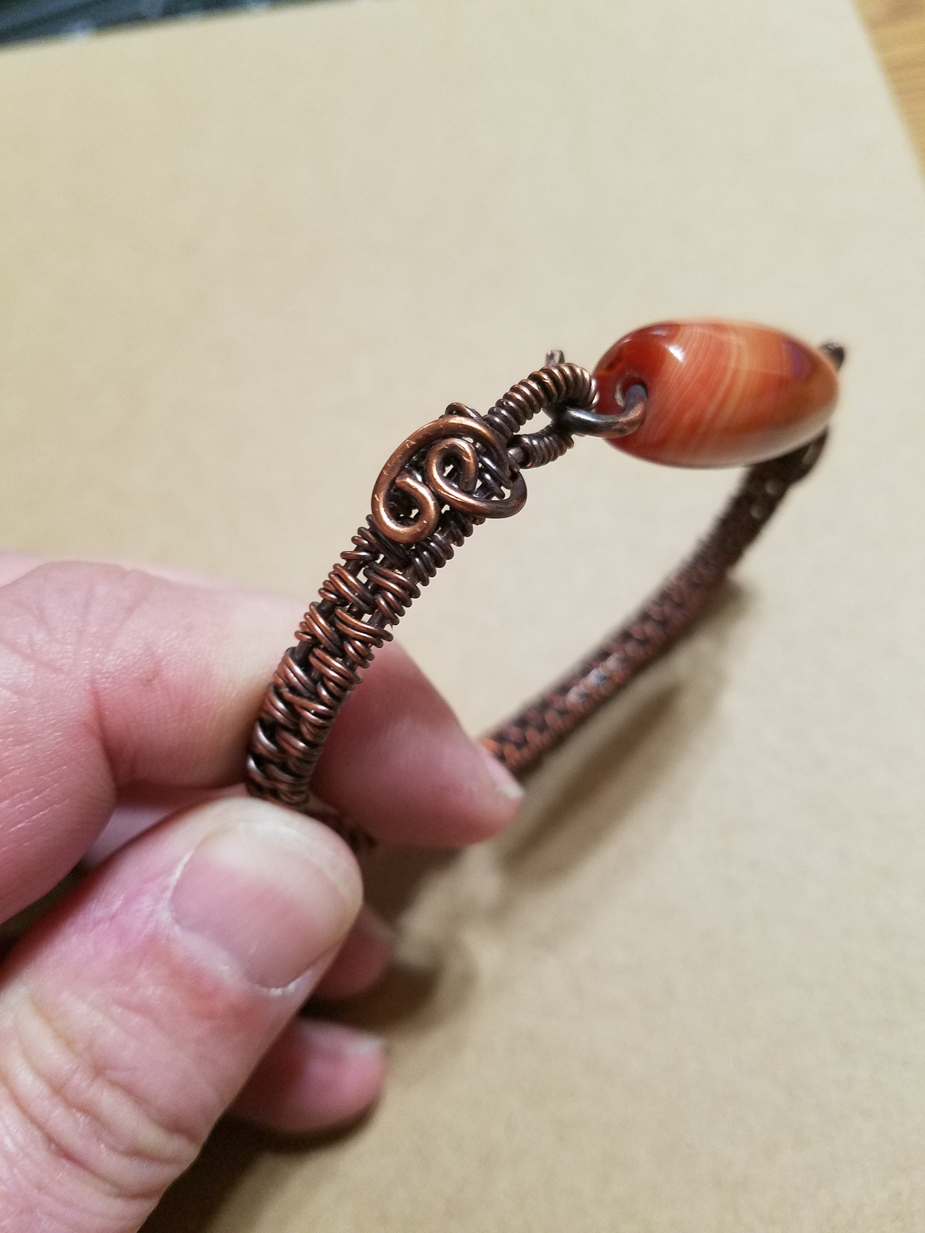 Slender woven copper bracelet with gemstone bead clasp